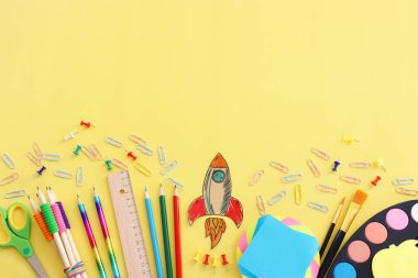 Okul konseptine geri dönelim. Pastel sarı arkaplan üzerindeki öğrenci kırtasiyesinin üst görünümü