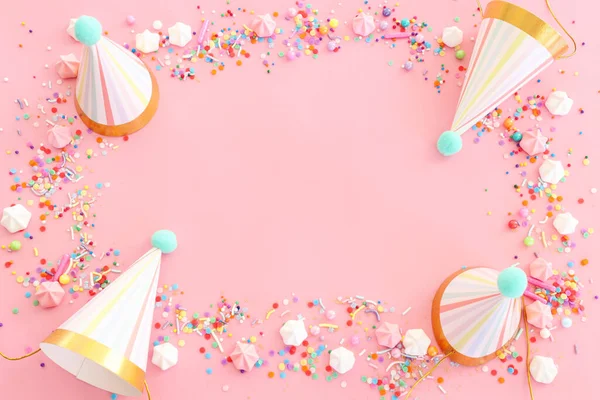 生日宴会背景 帽子和彩色糖果盖在粉红的粉红背景之上 顶部视图 — 图库照片