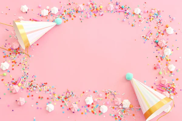 生日宴会背景 帽子和彩色糖果盖在粉红的粉红背景之上 顶部视图 — 图库照片