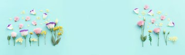Pastel mavi arkaplan üzerinde pembe, sarı ve mor çiçek kompozisyonu.