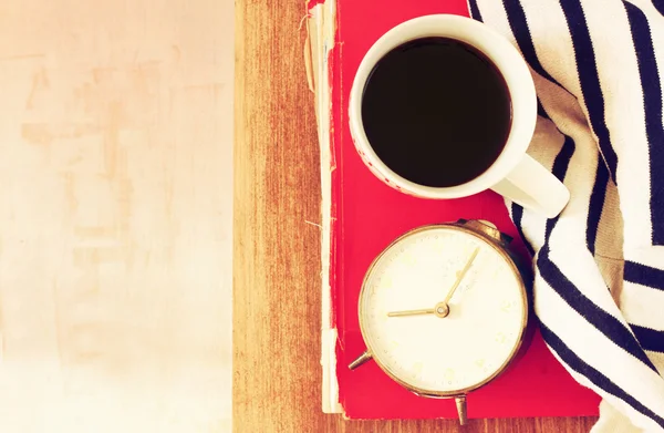 Draufsicht auf Kaffeetasse, altes Uhrenbuch und Decke über Holztisch. gefiltertes Bild — Stockfoto