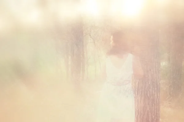 Foto surrealista de una joven de pie en el bosque. imagen es texturizada y tonificada —  Fotos de Stock