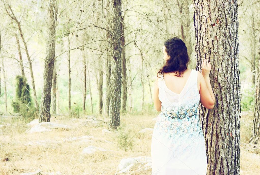 Surreal photo of young woman standing in forest. image is textured and toned