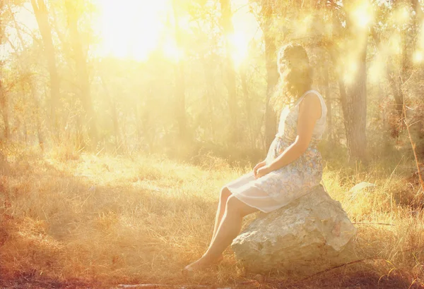 Surreal blurred background of young woman sitting on the tsone in forest — Stock Photo, Image