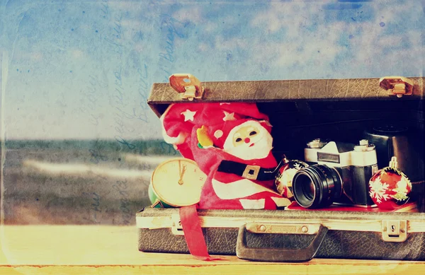 Open briefcase with christmas decorations and camera in front of beach view. christmas holiday concept. — Stock Photo, Image