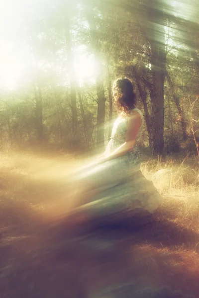 Surréaliste fond flou de jeune femme assise sur le tsone dans la forêt — Photo