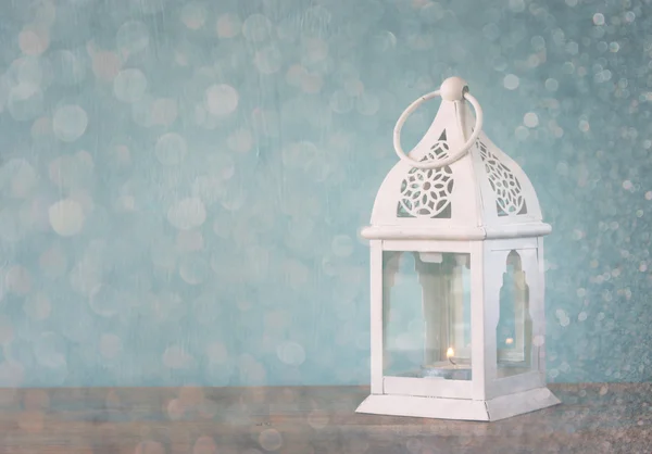 White lantern over wooden table and glitter lights background — Stock Photo, Image