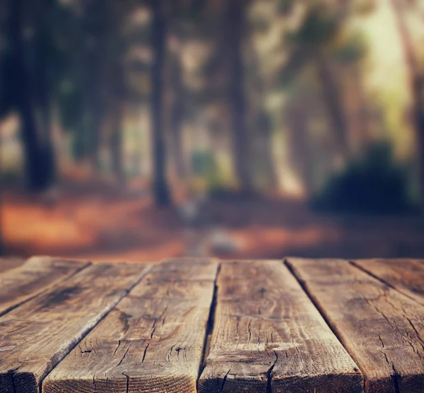 Imagen de tableros de madera rústica frontal y fondo de árboles en el bosque. imagen es retro tonificado Fotos De Stock