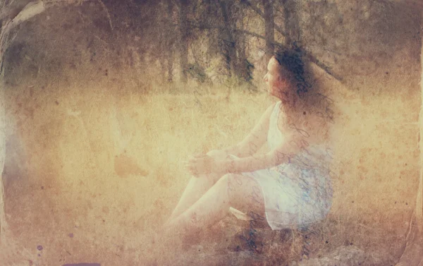 超现实主义： 背景模糊的年轻女子坐在森林里的石头上。抽象的、 梦幻般的概念。图像纹理和复古色调 — 图库照片