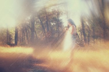 gerçeküstü arka plan bulanık bir genç kadın ormanda duruyor. soyut ve rüya gibi bir kavram. Görüntüyü dokulu ve retro tonlu