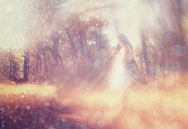 gerçeküstü arka plan bulanık bir genç kadın ormanda duruyor. soyut ve rüya gibi bir kavram. Görüntüyü dokulu ve retro tonlu