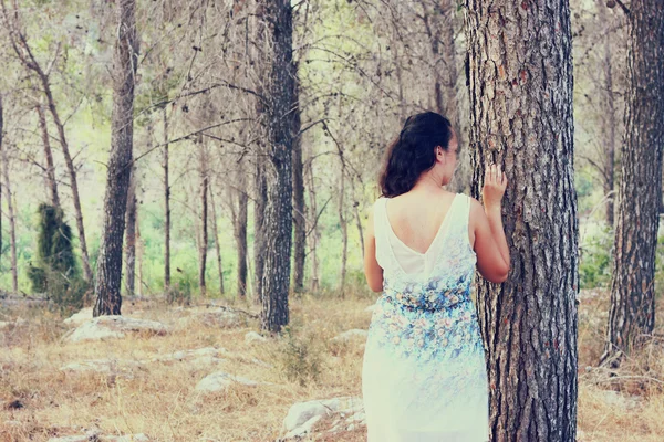 若い女性の超現実的な背景ぼかしの森に立ちます。イメージはレトロなトーン — ストック写真