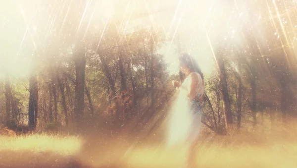 Surrealer verschwommener Hintergrund einer jungen Frau steht im Wald. abstraktes und verträumtes Konzept. Bild ist strukturiert und retro getönt — Stockfoto