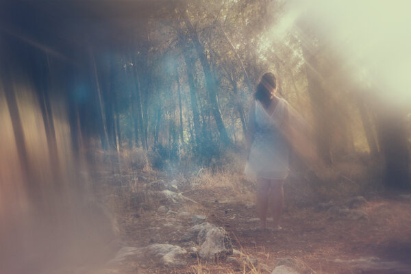 Surreal blurred background of young woman stands in forest. abstract and dreamy concept. image is textured and retro toned