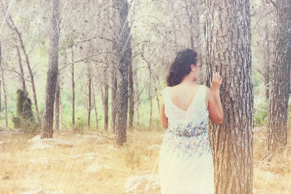 Surreale sfondo sfocato di giovane donna si trova nella foresta. immagine è retro tonica — Foto Stock