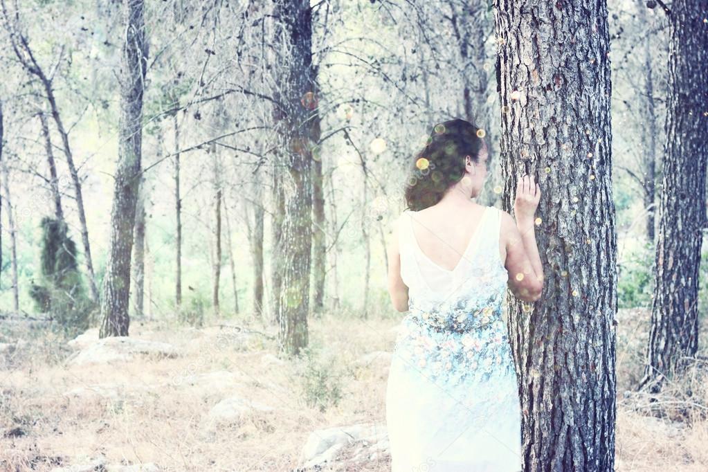 Surreal blurred background of young woman stands in forest