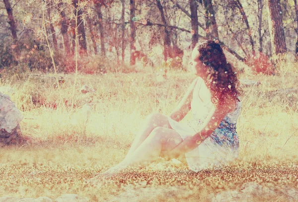 숲에 있는 돌에 앉아 젊은 여자의 초현실적인 배경을 흐리게. 추상적이 고 꿈결 같은 개념입니다. 이미지 질감 및 레트로 톤 — 스톡 사진