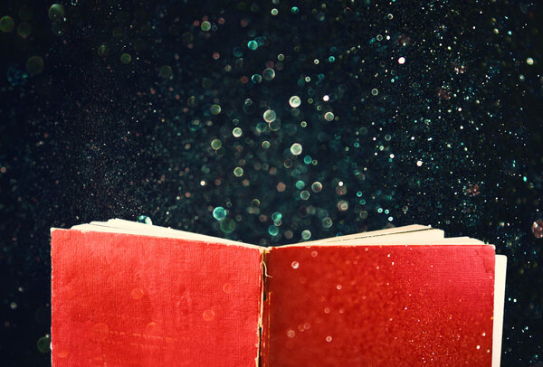 Open red book and glowing glittering lights
