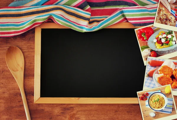 Vista superior de quadro-negro e colher de madeira sobre mesa de madeira e colagem de fotos com vários alimentos e pratos — Fotografia de Stock