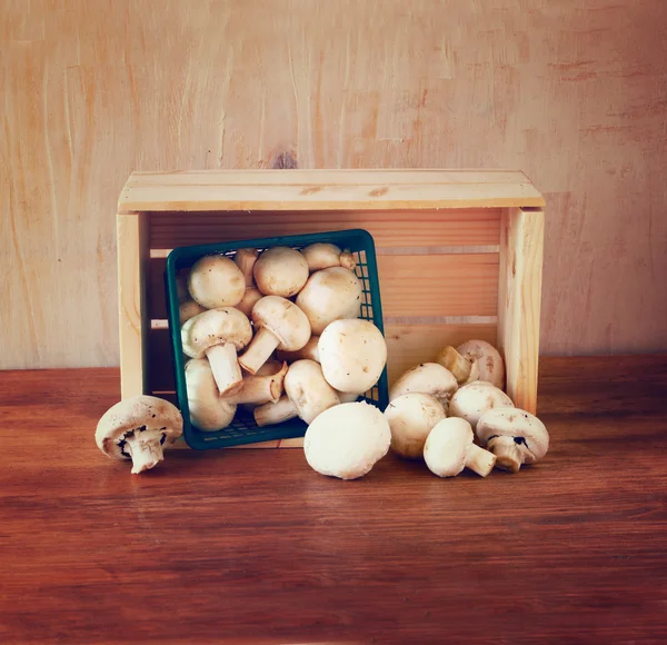 Fresh mufresh mushroom champignon in green rustic basket on wooden table — Stock Photo, Image