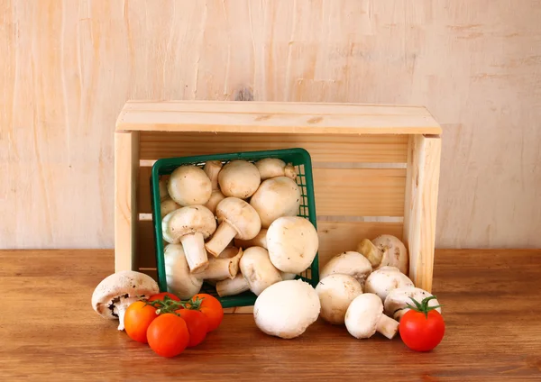 Fresh mufresh mushroom champignon in green rustic basket on wooden table — Stock Photo, Image
