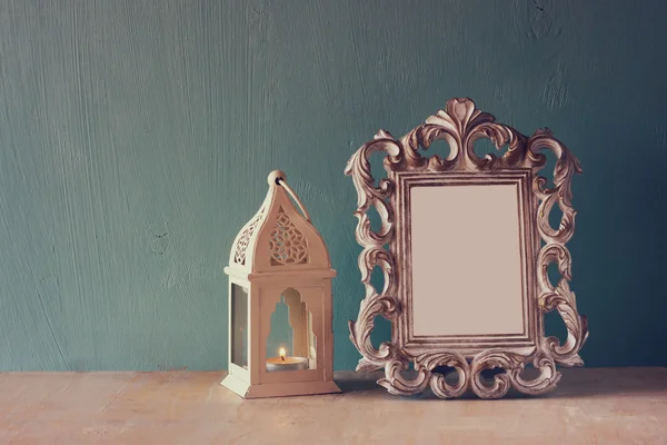 Imagen de clave baja de marco clásico antiguo vintage y linterna en mesa de madera. imagen filtrada —  Fotos de Stock