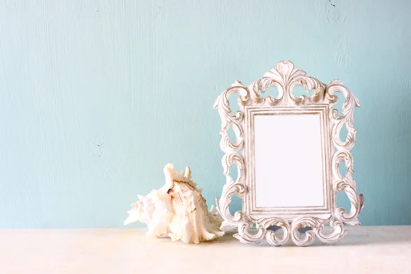 Lage sleutel imago van vintage antieke klassieke frame en Seashell op houten tafel. gefilterde afbeelding — Stockfoto