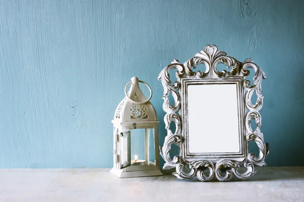 Imagen de clave baja de marco clásico antiguo vintage y linterna en mesa de madera. imagen filtrada — Foto de Stock