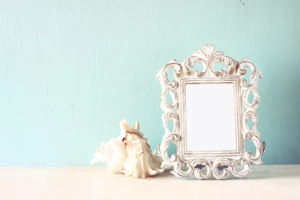 Low key image of vintage antique classical frame and seashell on wooden table. filtered image — Stock Photo, Image