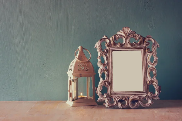 Low key image of vintage antique classical frame and white lantern on wooden table. filtered image — Stock Photo, Image