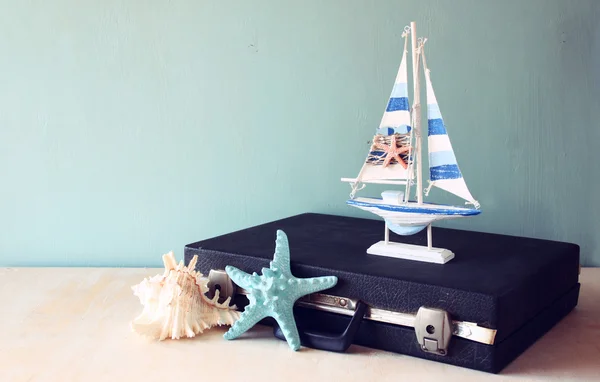 Old Vintage sutcase with toy boat' starfish and seashell  on wooden board. travel and voyage concept. retro filtered image — Stock Photo, Image