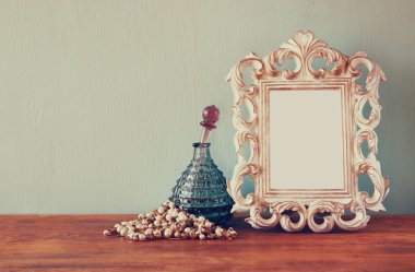 Vintage antik parfüm şişesi ile eski resim çerçevesi, ahşap masa üzerinde. Retro filtre uygulanmış görüntü