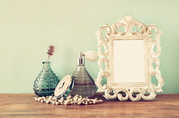 Garrafas de perfume antigas vintage com moldura antiga, na mesa de madeira. imagem retro filtrada — Fotografia de Stock