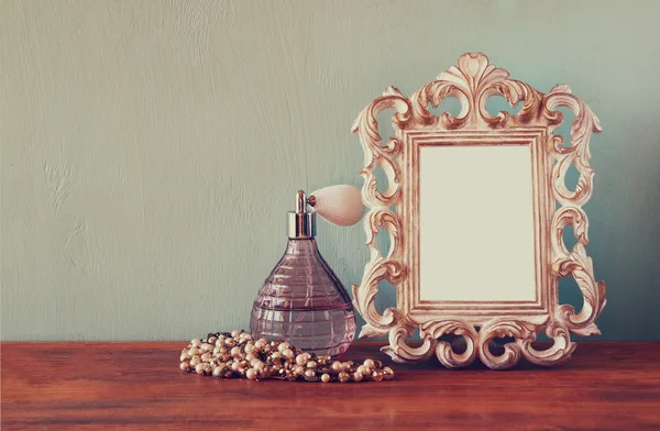 Vintage antique perfume bottle with old picture frame, on wooden table. retro filtered image — Stock Photo, Image