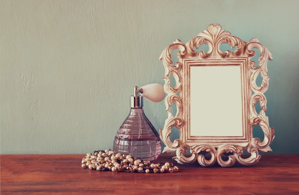 Vintage antieke parfumfles met oude schilderijlijst, op houten tafel. Retro gefilterde afbeelding — Stockfoto