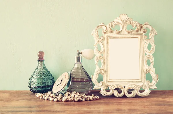 Vintage antieke parfumflesjes met oude schilderijlijst, op houten tafel. Retro gefilterde afbeelding — Stockfoto