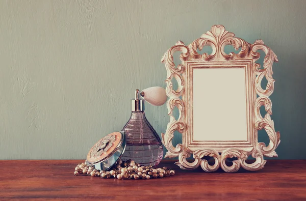 Vintage antike Parfümflasche mit altem Bilderrahmen, auf Holztisch. Retro gefiltertes Bild — Stockfoto