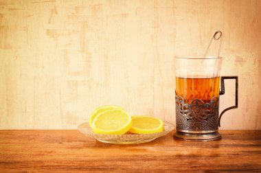 Ahşap masa üzerinde taze limon ile Vintage çay cam tutucu. Retro filtre uygulanmış görüntü