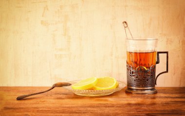 Ahşap masa üzerinde taze limon ile Vintage çay cam tutucu. Retro filtre uygulanmış görüntü