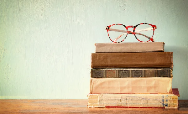Old books with vintage glasses on a wooden table. retro filtered image — Stock Photo, Image