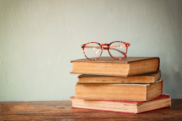 Alte Bücher mit Vintage-Gläsern auf einem Holztisch. Retro gefiltertes Bild — Stockfoto