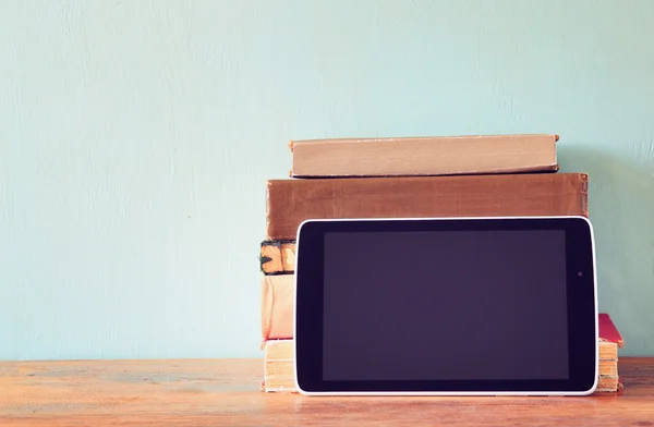 Stack of old books and tablet over wooden shelf. new technology concept. room for text — Stock Photo, Image