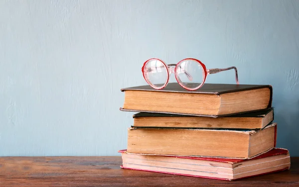 Alte Bücher mit Vintage-Gläsern auf einem Holztisch. Retro gefiltertes Bild — Stockfoto