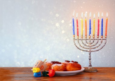 Jewish holiday Hanukkah with menorah, doughnuts and wooden dreidels (spinning top). clipart