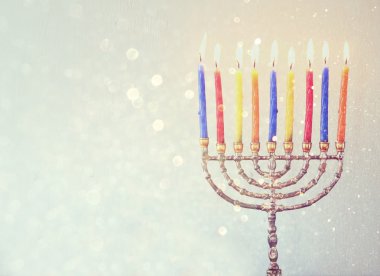 Low key image of jewish holiday Hanukkah background with menorah Burning candles over aqua glitter background clipart
