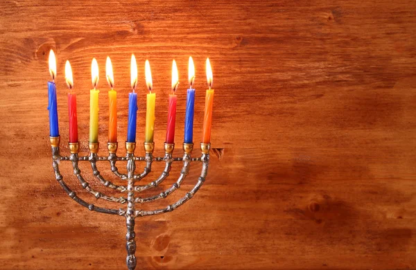 Low key image of jewish holiday Hanukkah background with menorah Burning candles over wooden background — Stock Photo, Image
