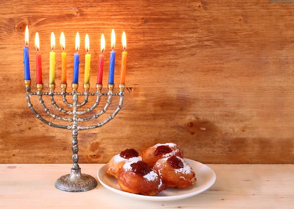 Jewish holiday Hanukkah with menorah, doughnuts and wooden dreidels (spinning top).