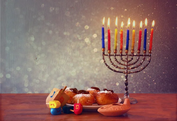 Joodse vakantie Chanoeka menorah, donuts en houten dreidels (spinnen boven). — Stockfoto