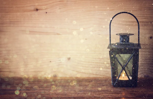 Lanterna vintage com velas em chamas, cones de pinho na mesa de madeira e luzes de brilho de fundo. imagem filtrada — Fotografia de Stock