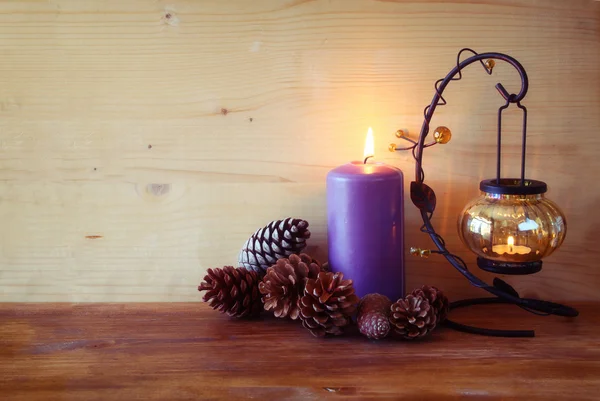 Lanterna vintage com vela em chamas e cones de pinho na mesa de madeira. imagem filtrada — Fotografia de Stock